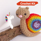 Small rainbow crocheted snail on a white background with a unicorn