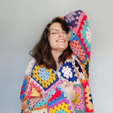 Brightly coloured y2k seventies feel granny square crochet cardigan being worn by a brunette white woman
