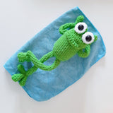 Happy looking green amigurumi crochet frog sitting on a white background