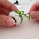 Close up of hands making the eyes of the amigurumi frog kit