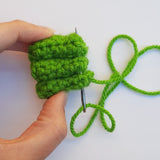 close up of maker sewng three crochet frog toes together