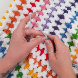 white hands making the rainbow blanket crochet kit